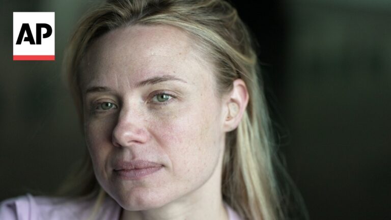 Close-up portrait of a woman with blonde hair and green eyes, looking slightly off-camera, with an AP logo in the upper-left corner indicating a news photo.