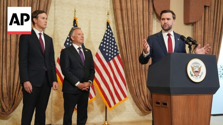 Three men in suits at a press conference; one speaks at a podium with the presidential seal, two others stand nearby as flags wave in the background. (AP logo in corner)