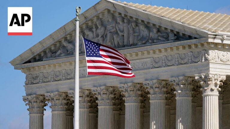 AP photograph: the American flag waving in front of a marble neoclassical courthouse with tall columns and a sculpted pediment, upper-left AP logo visible.