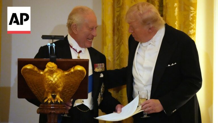 Two elderly men in tuxedos share a laugh at a formal event, standing by a podium with a gold eagle emblem; AP logo visible in the corner.