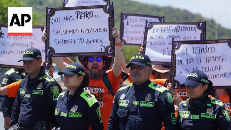 AP photo of uniformed police officers at a protest, holding handwritten signs in Spanish (e.g., 'Salvemos a Colombia').