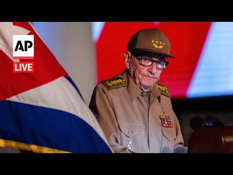 Senior military official wearing khaki uniform and cap with ribbons speaks at a podium; a flag is in the foreground with AP Live watermark in the corner.