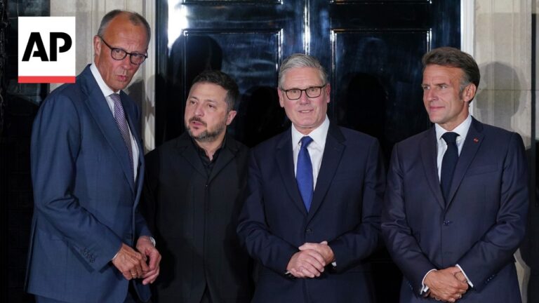 Group of four men in suits posing for a photo outside a dark doorway; AP logo visible on the left.