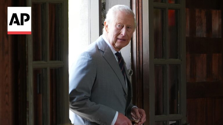 Older man in a light gray suit standing in a doorway, looking toward the camera, with an AP logo in the corner.