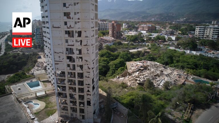 Tall, damaged apartment building with shattered windows next to a collapsed concrete pile in a coastal city near mountains? (informative)