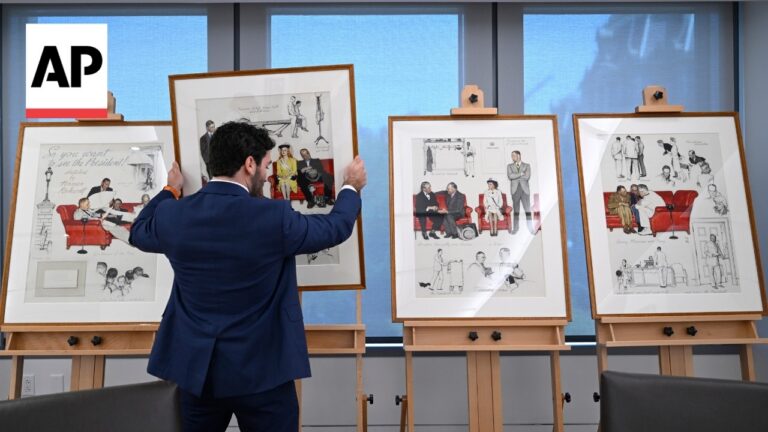 Man in a navy suit adjusts framed political cartoons on display easels in a bright gallery, AP logo visible in the background.