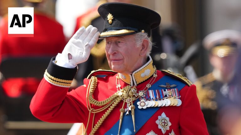 Older man in a red ceremonial military uniform saluting, with white gloves, medals, and gold braids; AP logo top-left.