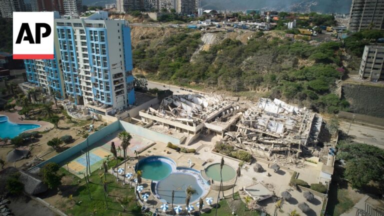 Aerial view of a demolished building beside a blue high-rise, with resort pools and palm trees in the foreground and the AP logo in the corner.