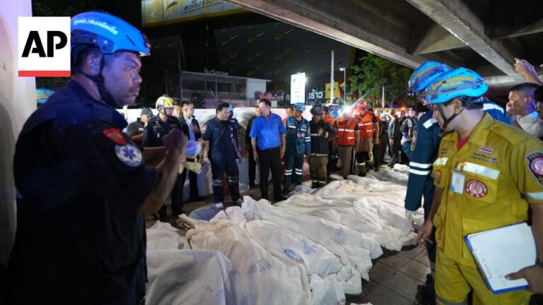 AP photo: emergency responders stand around white body bags laid out on a street at night under an overpass
