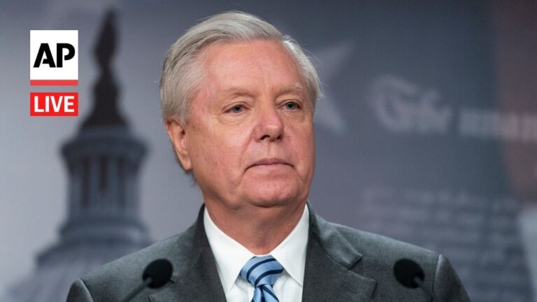 Man in a gray suit and blue striped tie speaks at a press conference, AP Live logo in the top-left.