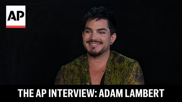 Adam Lambert smiling during an AP interview video, with the AP logo in the corner and the title The AP Interview: Adam Lambert at the bottom.