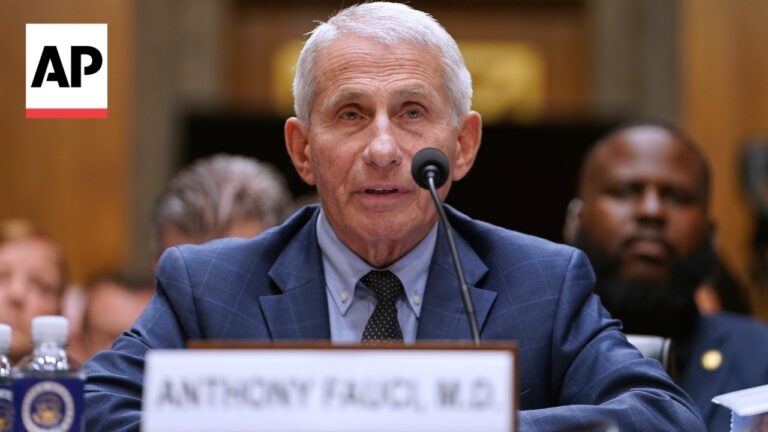 Older man in a blue suit speaks into a microphone at a hearing, AP logo visible in the corner.