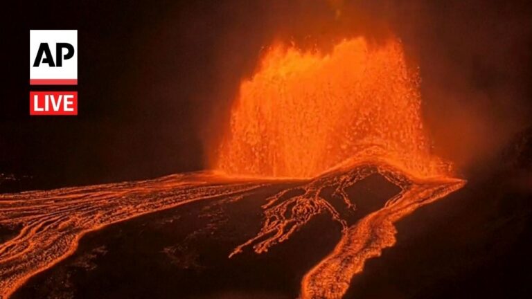 Volcanic eruption at night with a column of molten lava spraying upward and lava rivers flowing across the ground; AP Live watermark.