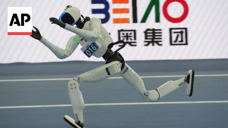 Humanoid white robot sprinting on a blue track with arms extended; AP logo in the corner and Chinese characters on a banner behind.