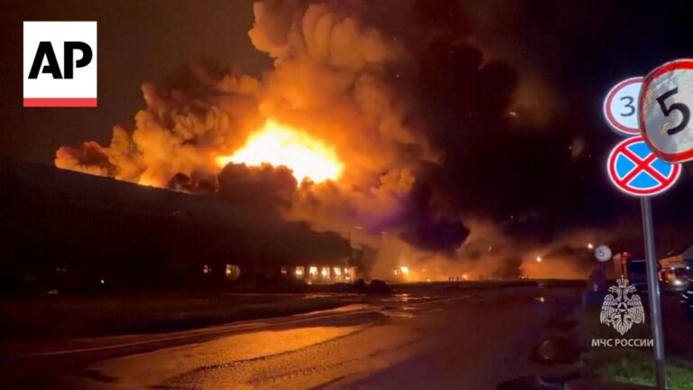 Nighttime explosion with massive flames and dark smoke, emergency vehicles likely present (AP watermark).