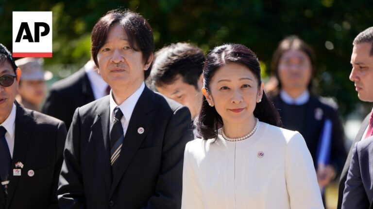 AP watermark in the corner; group of formally dressed officials at an outdoor event, with a woman in a white suit in the foreground.