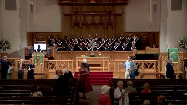 Chorus of uniformed singers on a church choir loft behind the altar during a service.