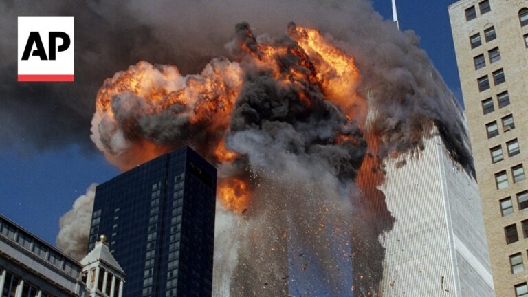 AP logo visible in the corner; a skyscraper is engulfed in flames and thick black smoke during the 9/11 attack, with debris falling.