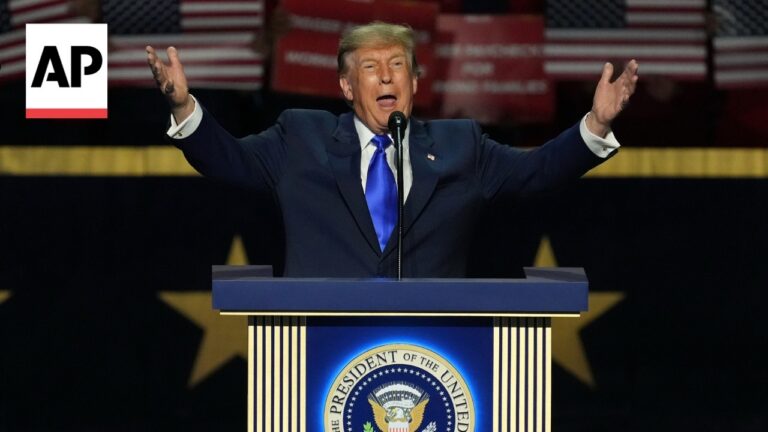 Former President Donald Trump speaks at a podium with arms raised; AP logo in the corner.