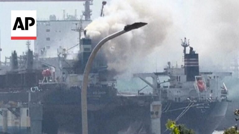 Large cargo ship at a port emitting thick smoke from its funnel; AP watermark in the corner.
