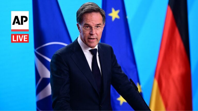 Male politician at a podium giving a press briefing, with EU and German flags in the background and an AP Live logo on the left.