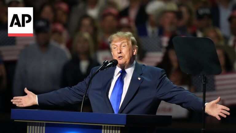 Former US President Donald Trump speaks at a podium with arms outstretched; AP logo visible in the upper left corner.