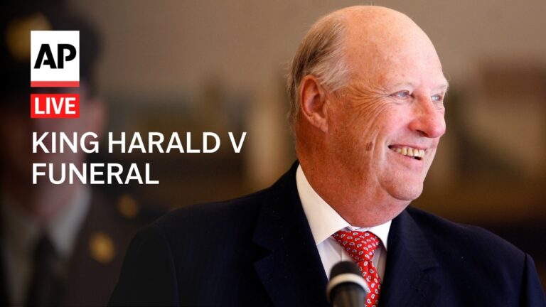 AP Live: King Harald V funeral — smiling elderly king in a dark suit with a red tie at a microphoneStatue.