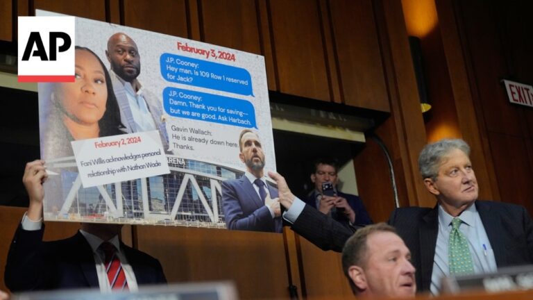 AP logo on a large collage board held by a suited man at a press briefing, featuring text messages and photos in the background