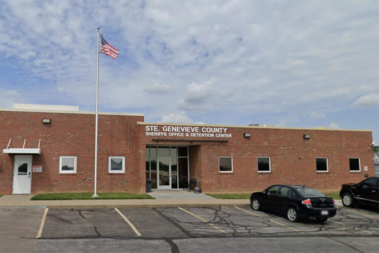 Brick sheriff's office and detention center with American flag on a tall flagpole in front.